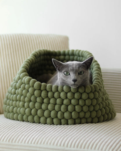 Cozy basket-style cat bed made from handmade New Zealand wool featuring a peek-out design for playful cats. 1